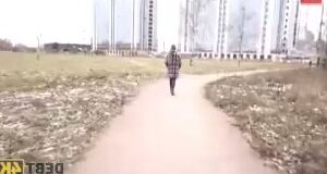 Woman in Plaid Coat Walking on Dirt Path Near Apartment Buildings