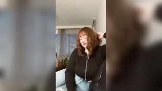 Brunette with Bangs in Black Zip-Up Hoodie and Jeans Smiles at Camera