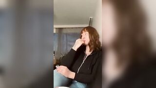 Brunette with Bangs in Black Zip-Up Hoodie and Jeans Smiles at Camera