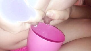 Young cougar pours milk from breasts inside a cup