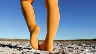 Barefoot walking by dried up lake inside yellow stockings