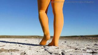 Barefoot walking by dried up lake inside yellow stockings