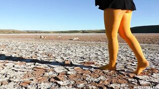Barefoot walking by dried up lake inside yellow stockings