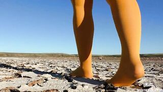 Barefoot walking by dried up lake inside yellow stockings