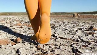 Barefoot walking by dried up lake inside yellow stockings