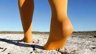 Barefoot walking by dried up lake inside yellow stockings
