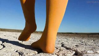 Barefoot walking by dried up lake inside yellow stockings
