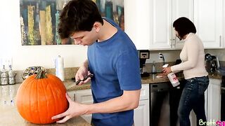 Alex D. carves a hole in a pumpkin for Halloween while his mother cleans the kitchen. He leaves the guts