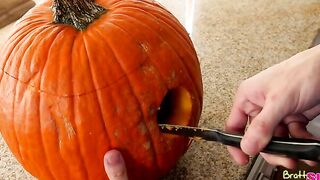 Alex D. carves a hole in a pumpkin for Halloween while his mother cleans the kitchen. He leaves the guts