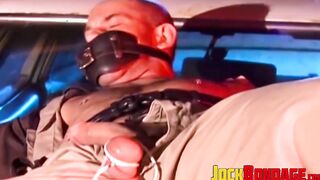 Submissive police officer tied up on the hood of a car