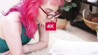 Attractive chick with glasses is lying on the floor and writing something inside her notebook