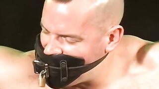 Bigg Pette has  his hands bound with leather and his balls roped down to his toes